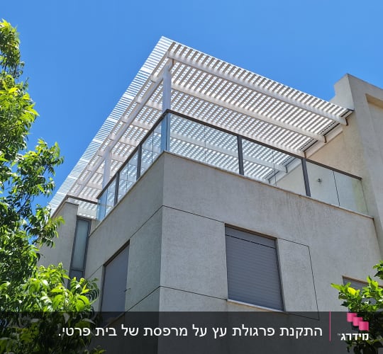בניין עם פרגולה ועצים ברקע ביום שמשי